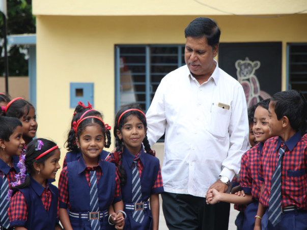 Schoolchildren with a member of the school community outside Gayathri Higher Primary School
